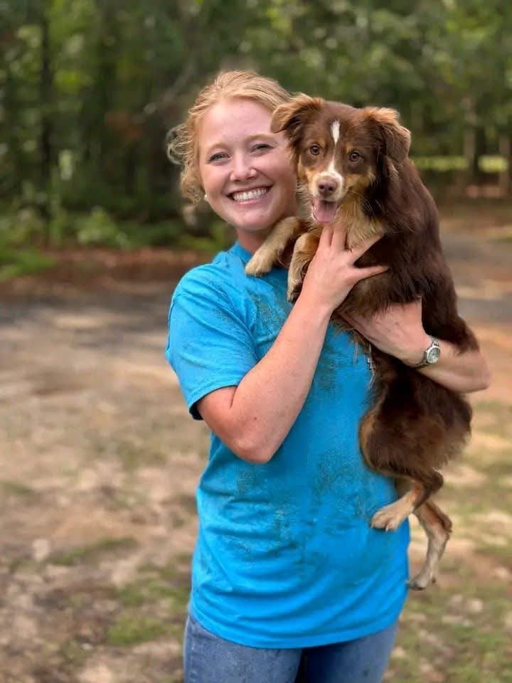 Woman holding her Australian Shepherd outdoors